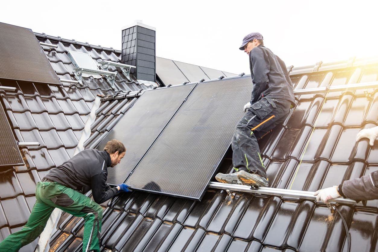 Erfahrene Facharbeiter bei der Dachmontage von Solarmodulen PV-Anlagen Installation auf dem Dach mit Verlegung der Solarmodule von erfahrenen Facharbeitern